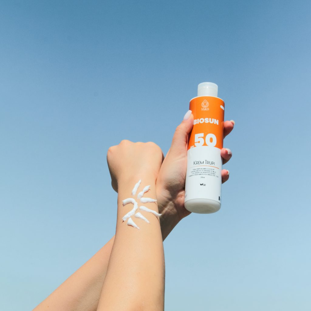 arm with sunscreen applied in sun design and hand holding sunscreen bottle
